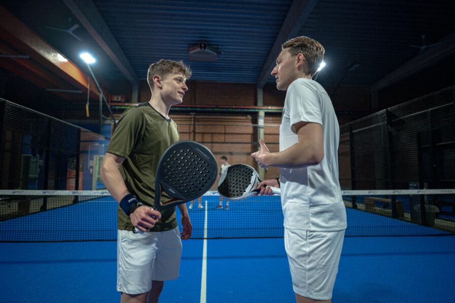 To padelspillere holder deres egne padelbat op mod hinanden ved nettet
